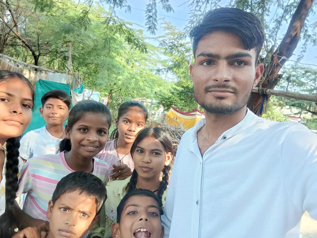 A Helping Hut volunteer takes a sunny selfie with a group of smiling Udaan Street School children in their neighborhood.