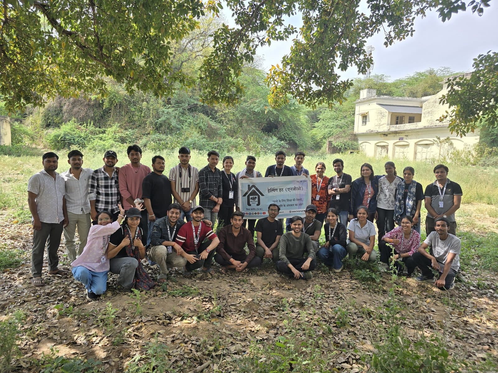 The Helping Hut team holding the GyanKutir banner in a field at Gopalpura