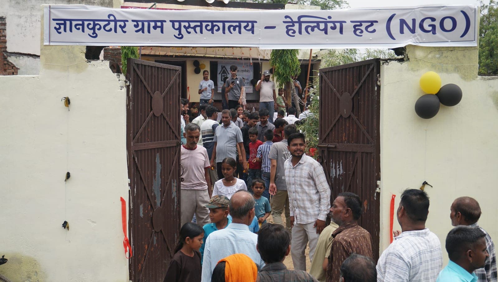 Villagers streaming through the gate under the GyanKutir Gram Pustakalaya banner on inauguration day