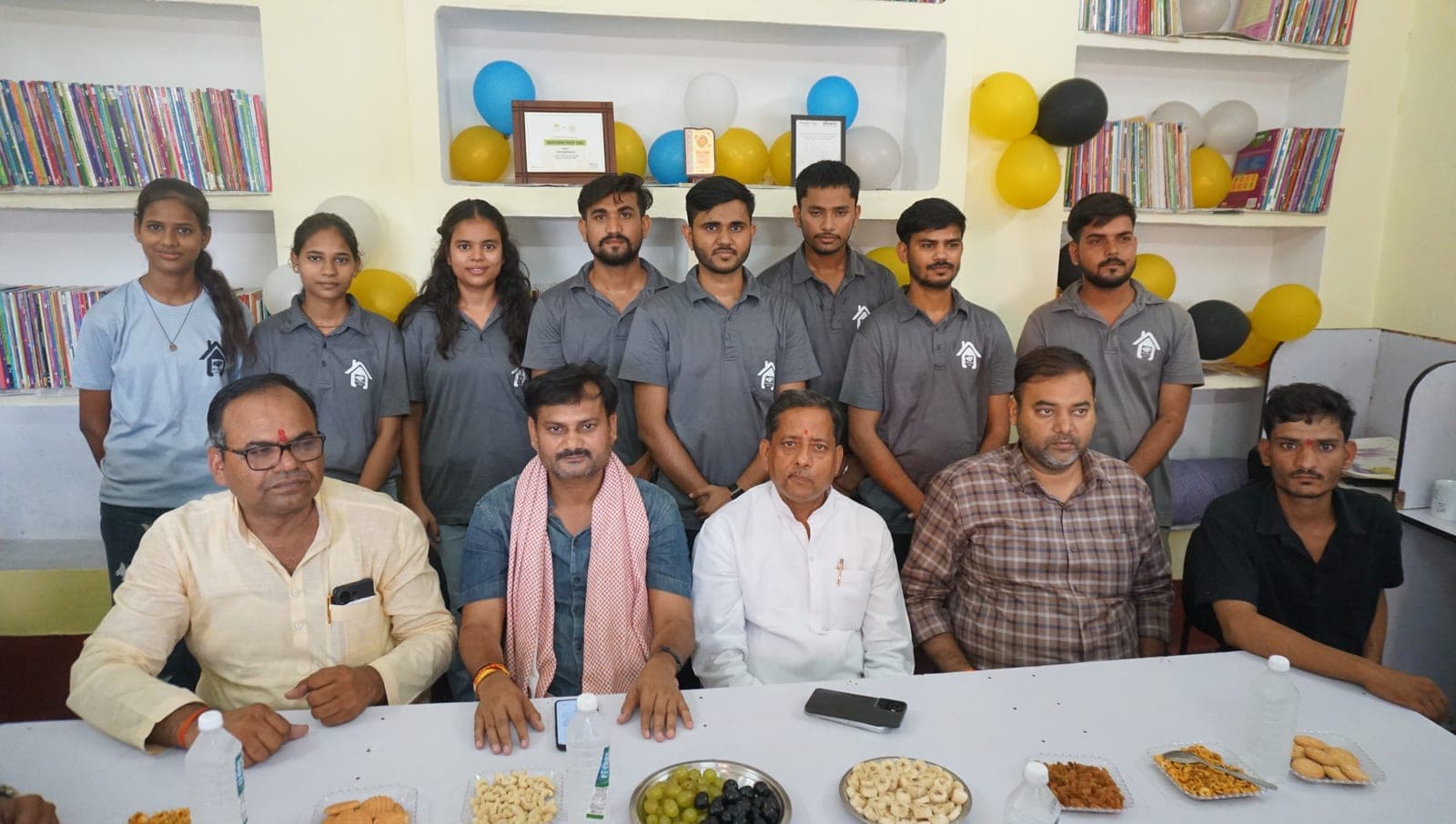 The Helping Hut team and chief guests inside the library with stocked bookshelves behind them