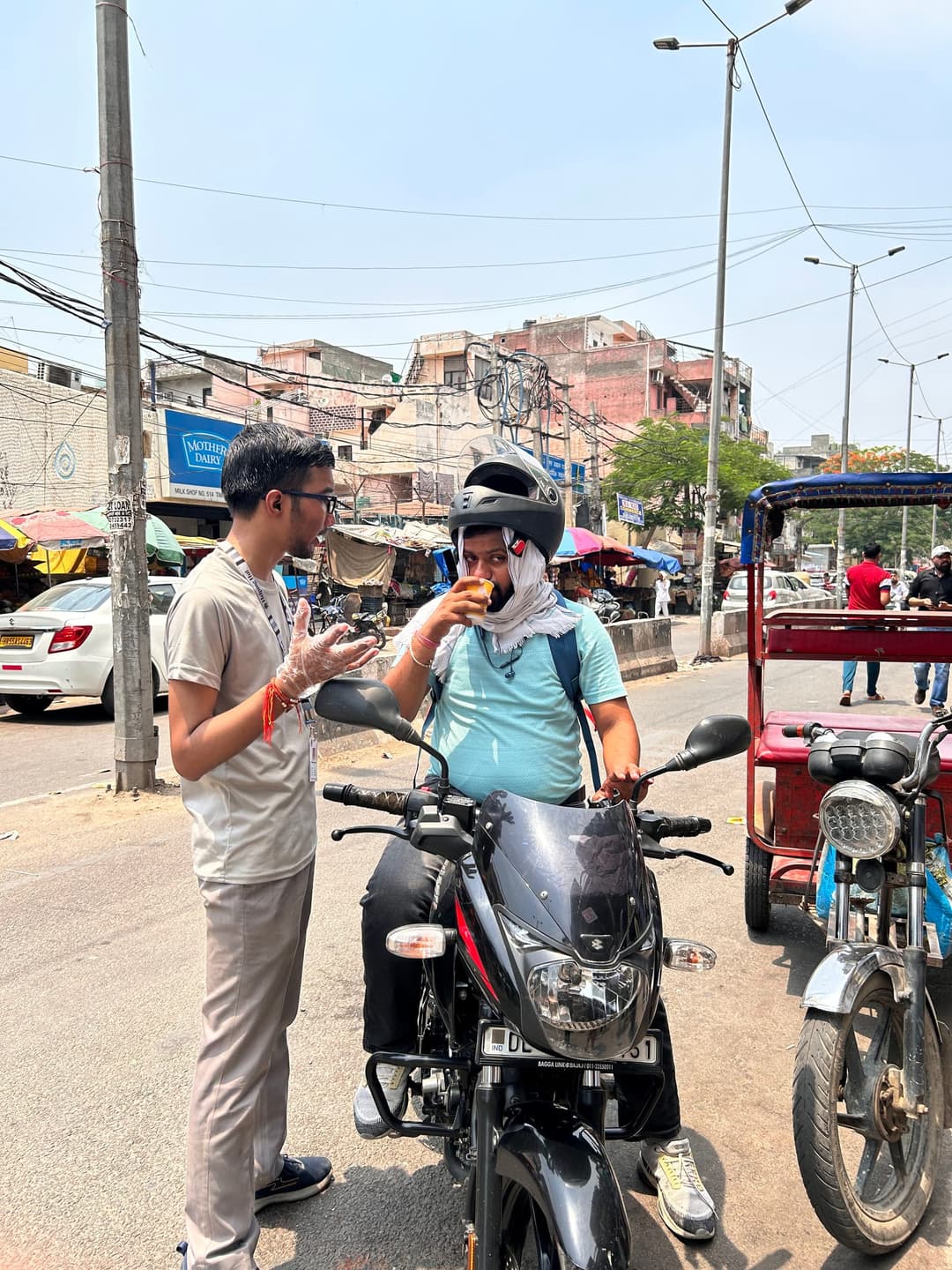 A Helping Hut volunteer chats with a motorcyclist who pauses at the roadside to drink a cup of refreshment handed out during a street distribution drive.