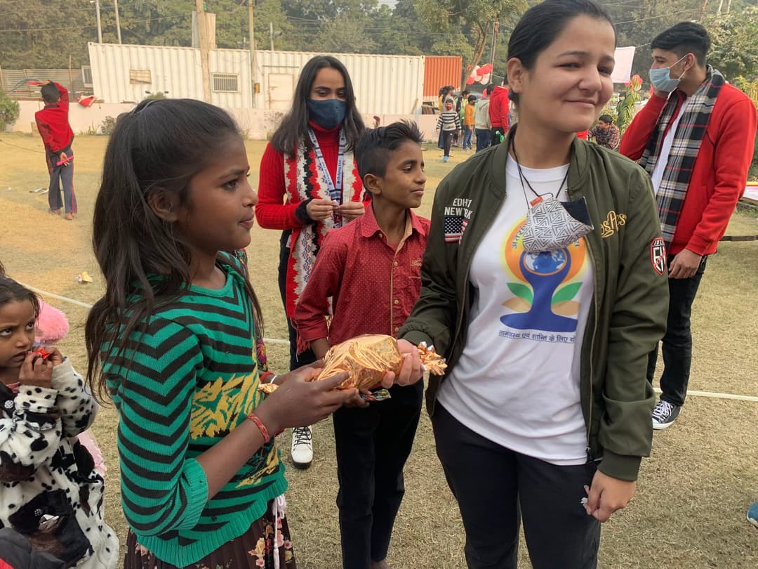A Helping Hut volunteer handing a wrapped gift to a girl at the carnival