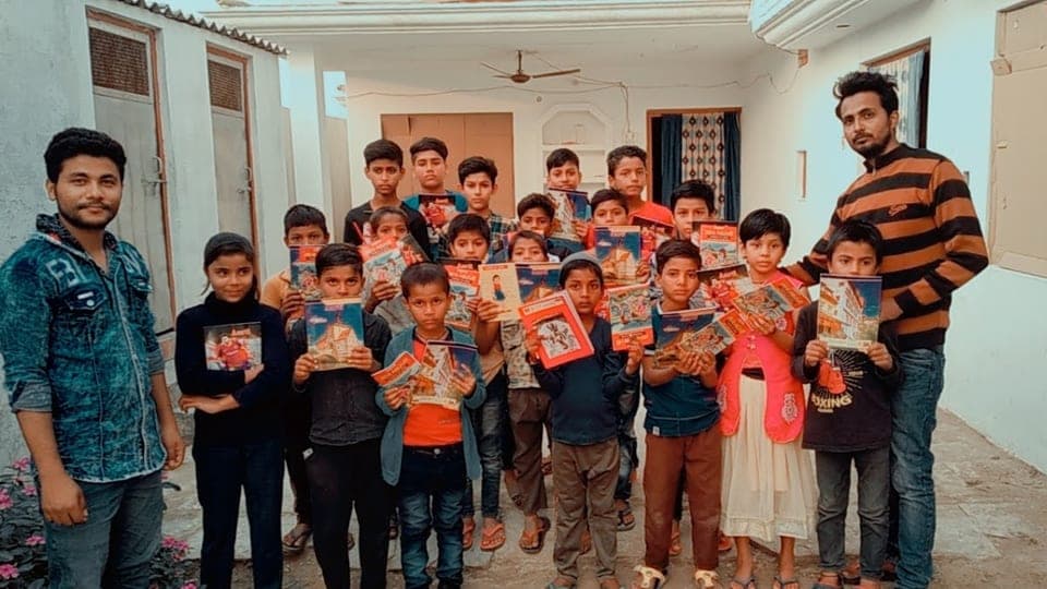 Helping Hut volunteers with children holding snack packets during a food distribution drive in Chandauli