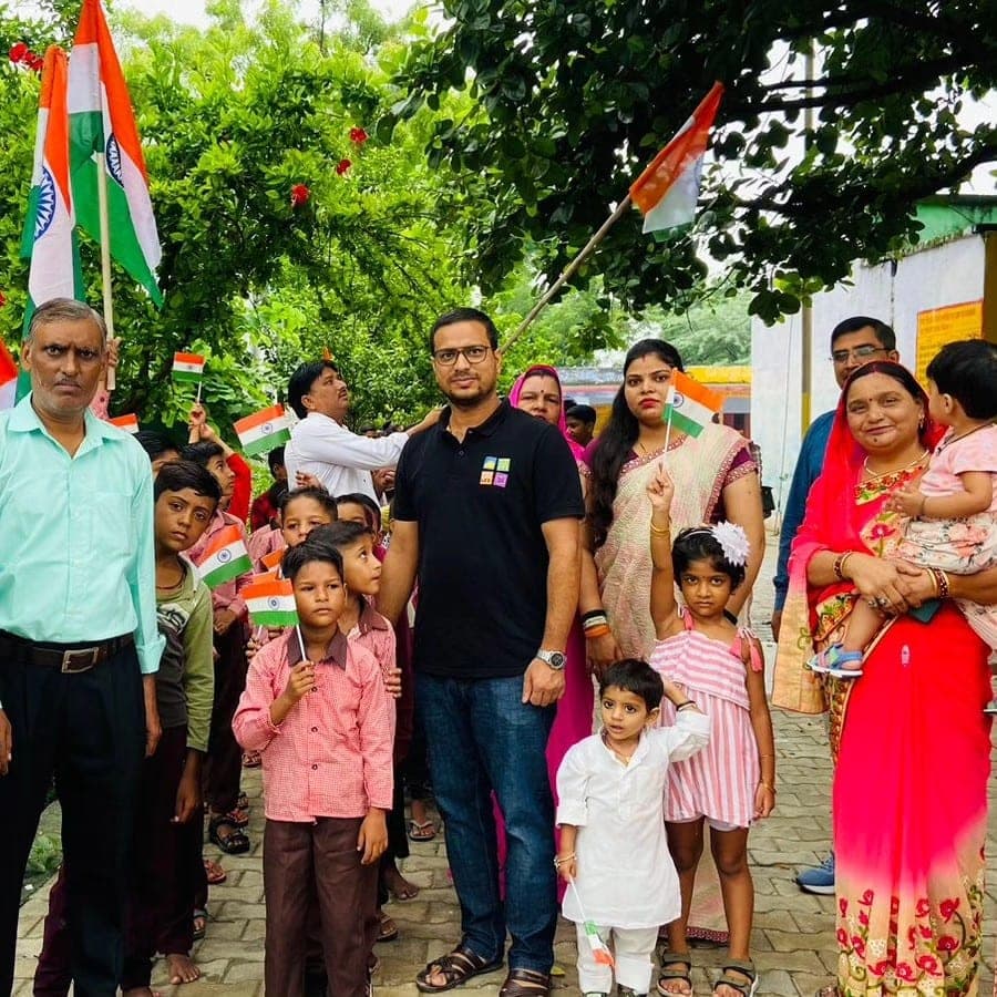 Helping Hut volunteers celebrating Independence Day with schoolchildren and families holding Indian tricolour flags in Hathras