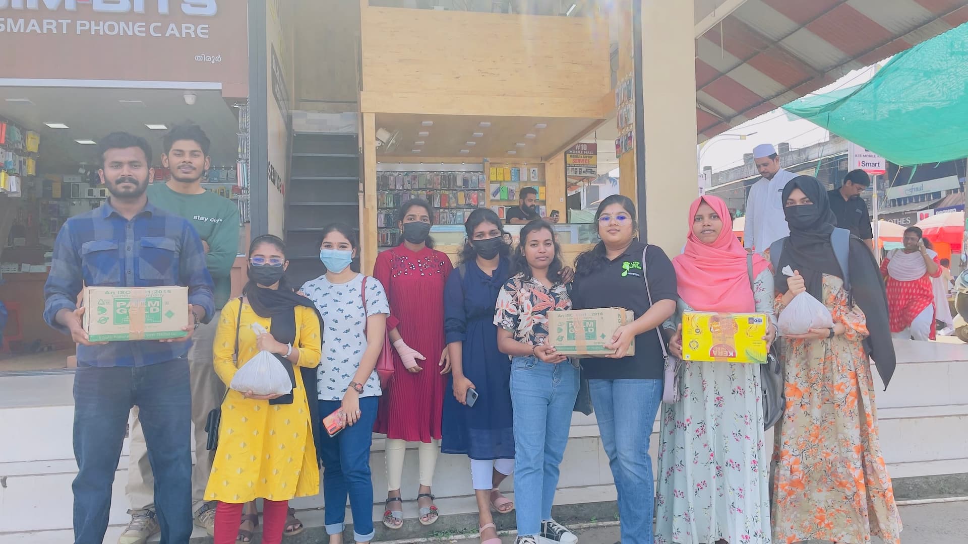 Helping Hut volunteers in Thrissur, Kerala holding boxes and bags of food supplies for a street distribution drive
