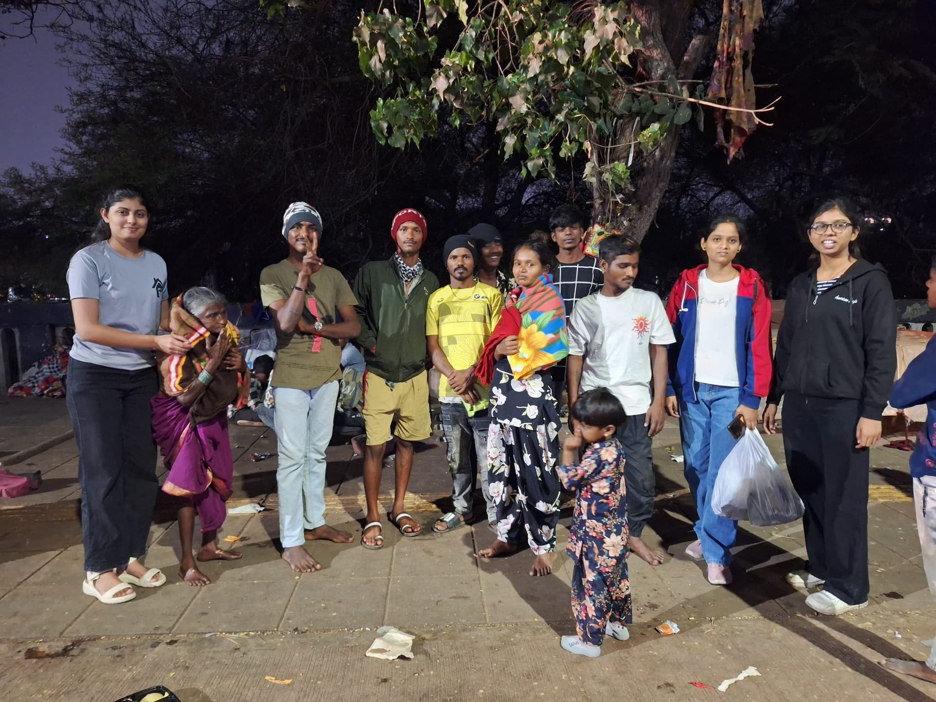 Helping Hut volunteers with homeless families during a night outreach distribution drive in Pune